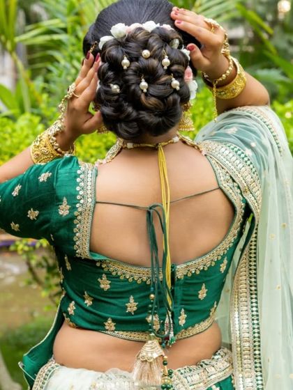 The back view showcases a stunning bridal bun decorated with pearls and flowers, and the detailed embroidery on the back of the green silk blouse.