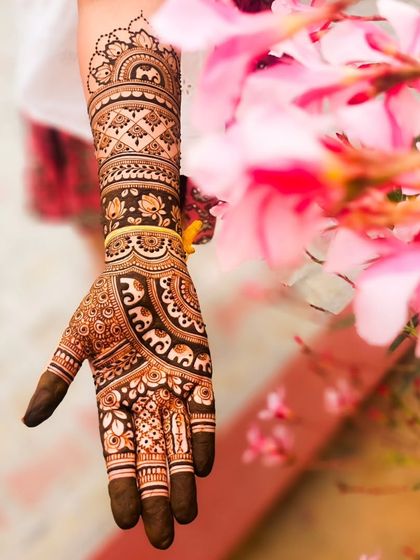 A beautifully composed shot with a floral background, this image highlights the delicate elephant and lotus band on the arm.