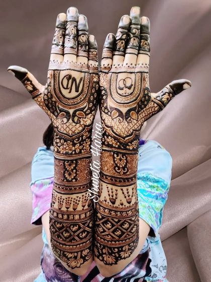 A beautiful pose showcasing a full-coverage engagement design, with the couple's initials and engagement rings drawn on the palms, surrounded by peacock and geometric patterns.