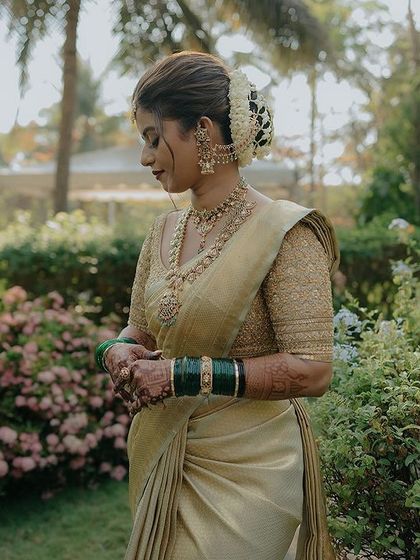A serene moment captured in a garden setting. The bride wears a classic gold Kanchivaram with a matching embroidered blouse, a timeless choice for a muhurtham.
