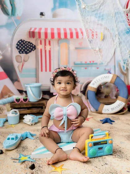 A sweet baby girl enjoying her own beach day in a cute bow swimsuit.