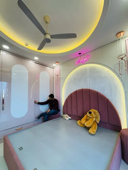 A dream room for a little one. We designed this baby pink kids' room with a custom arched headboard, a full-height sliding wardrobe for ample storage, and fun neon lighting to create a space that is both playful and practical.
