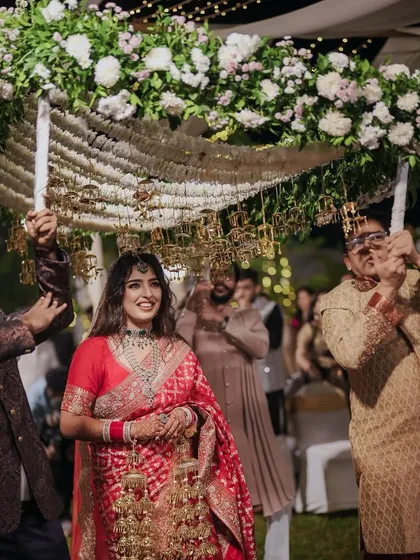 The bride's grand entrance under a magnificent phoolon ki chadar, held by her loved ones. We designed this floral canopy to be a beautiful frame for this emotional moment.