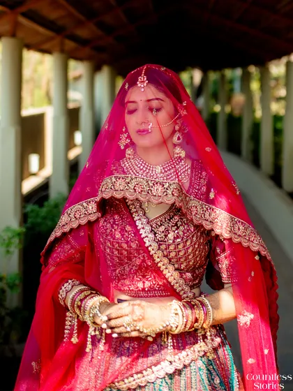 A moment of serene beauty. The bride, in her stunning pink lehenga and veil, takes a quiet second for herself. This portrait captures her elegance and the peaceful anticipation of the ceremony.