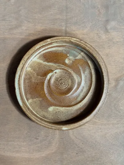 A handmade stoneware plate with a rustic, earthy glaze. The spiral pattern is a signature of my thrown work, and the unique glaze variations mean no two plates are ever the same.