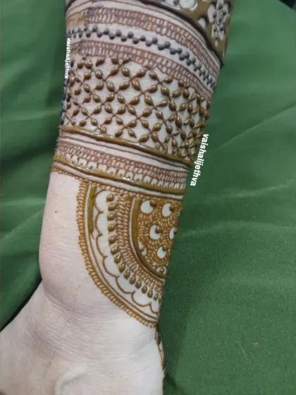 A detailed look at a back-hand wrist design. The combination of different bands with intricate patterns creates a beautiful cuff-like effect.