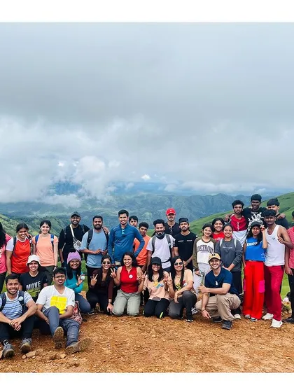 A large group photo at the Netravati summit, with the clouds creating a stunning background.