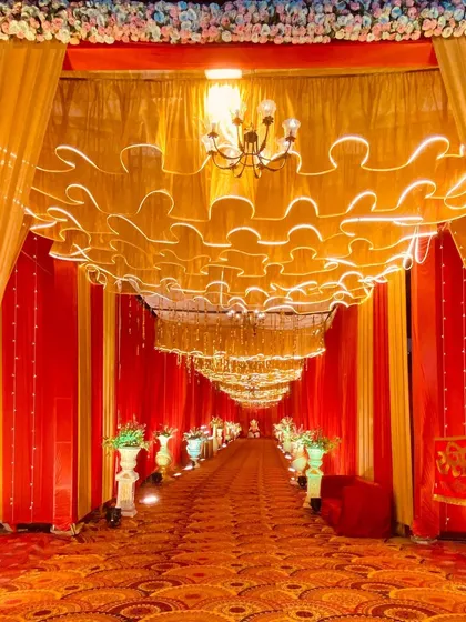 An opulent entrance with a ceiling of illuminated golden ruffles and hanging chandeliers, perfect for a grand wedding.