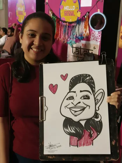 A happy festival-goer with her caricature, complete with little hearts. The festive background adds to the fun of the photo.