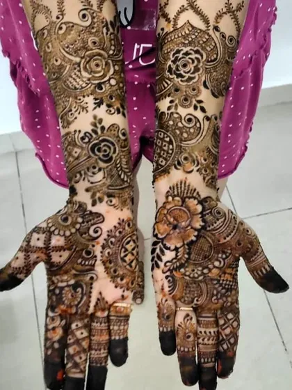 The dark fingertips in this design are a traditional touch that beautifully contrasts with the intricate floral and vine patterns on the hands and arms.