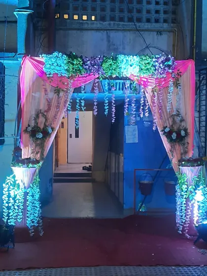 A beautiful entrance arch decorated with flowing drapes and hanging floral arrangements, lit with blue and white lights for a dreamy effect.