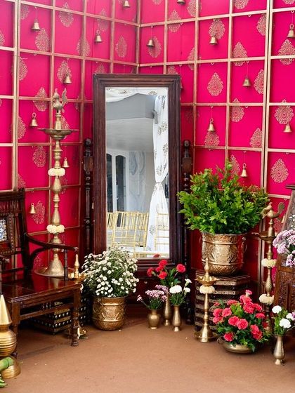 Another angle of the traditional photo corner, highlighting the full-length mirror, antique furniture, and lush floral arrangements against the bright pink wall.