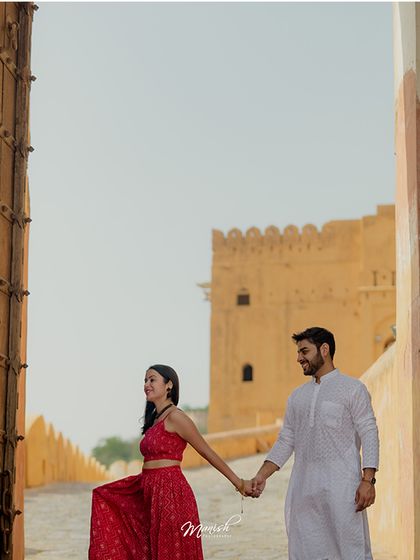 The couple holds hands as they walk through the grand gates of the fort, a symbolic start to their journey together.