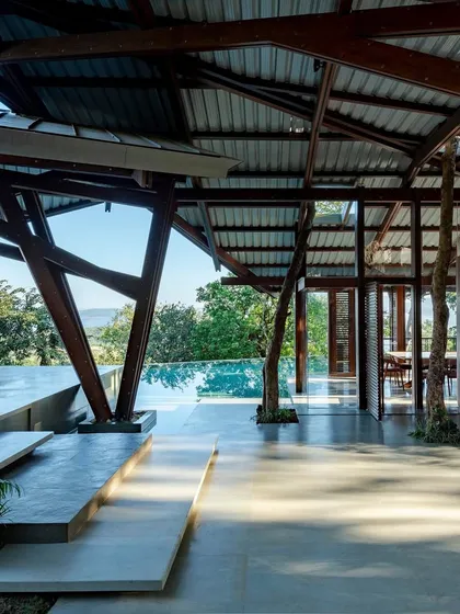 The Lateral Verandah House finds its footing on a sloping hill in Lonavala, its unique timber frame creating a dialogue with the landscape. We used raw basalt walls to ground the structure, a nod to the region's architectural history, creating a space that feels both of the earth and elegantly light.