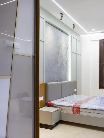 This view shows the relationship between the bedroom and the walk-in closet. The stone accent wall and neutral palette create a calm backdrop for daily life.