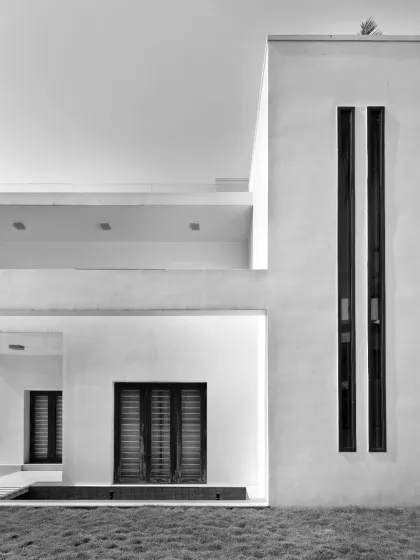 Minimalism reimagined with linear elegance. This facade detail embraces purity and precision through its stark white volumes and slender vertical window openings.