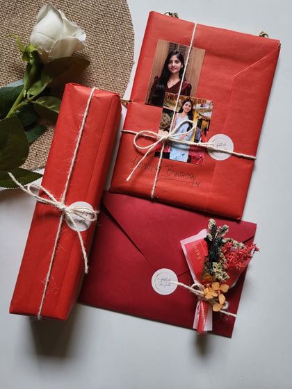 A beautifully wrapped set of birthday gifts in red paper, tied with simple twine. The presentation makes the gift even more exciting to receive.
