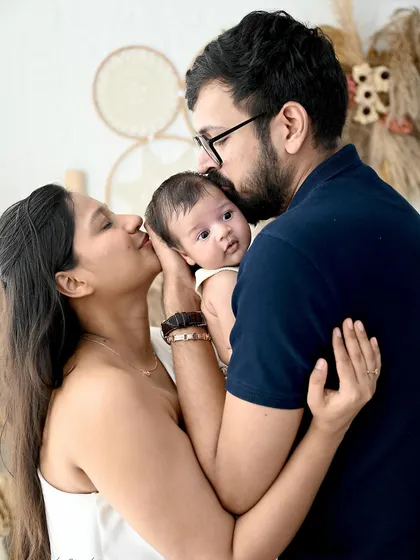 A tender family embrace. The parents shower their newborn with kisses, a beautiful and emotional moment captured in our warm and inviting boho studio.