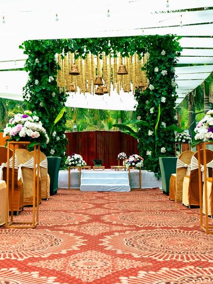 The aisle view of the green and gold themed mandap. The patterned carpet leads the eye towards the stage, creating a sense of anticipation and grandeur.