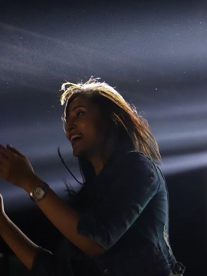 A beautiful, atmospheric shot of me on the mic, with the stage lights creating a halo effect. A moment of pure performance magic.