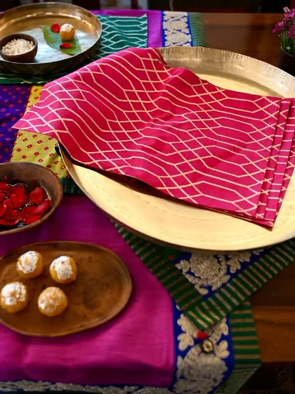 A pink brocade placemat from the same set, showcasing the beautiful geometric pattern and rich texture of the fabric.