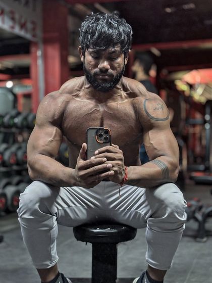 A seated pose, showing the chest striations and shoulder veins. This is the result of a strict diet and intense training.