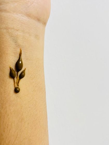 A tiny, simple leaf bud on the wrist, the perfect example of a minimal henna tattoo.