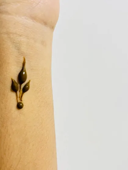 A tiny, simple leaf bud on the wrist, the perfect example of a minimal henna tattoo.