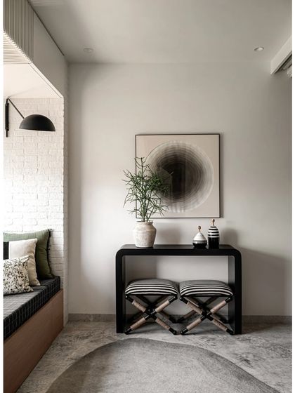 The living-cum-guest room is enhanced with a chic black console table and striped stools. This corner shows how a multi-functional space can still be elegant and uncluttered, with ample concealed storage.