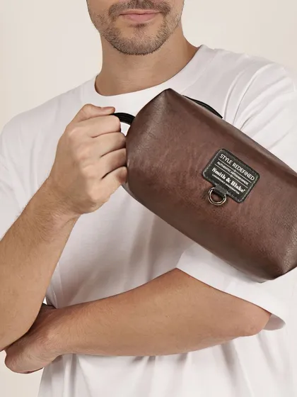 A close-up of a man holding a brown leather pouch. This highlights the product's texture and compact size, showing how it's held and used.