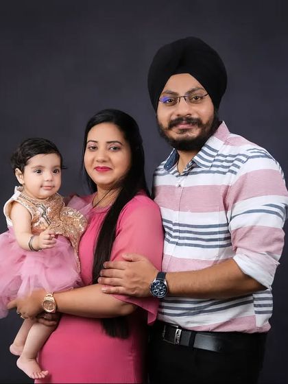 A stunning family portrait against a dark grey background. The daughter's sparkling dress and the family's loving embrace make this a standout photo.