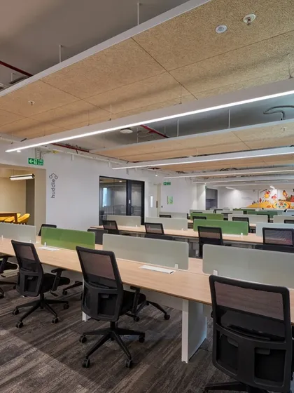 An open workspace with long benching-style desks to promote collaboration. The use of wood-fiber acoustic panels on the ceiling helps to control noise in the open environment.