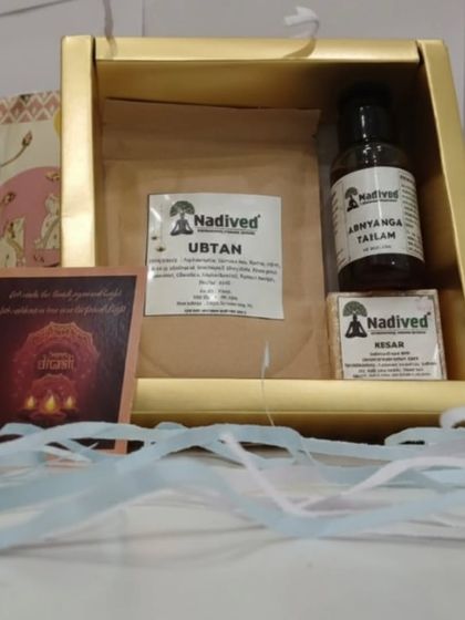 Another view of the Abhyanga Snan gift set, highlighting the natural products and the traditional greeting card included within the elegant gold box.