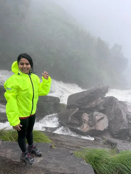 A trekker posing by the gushing Bandaje waterfalls, feeling the spray and the power of nature.