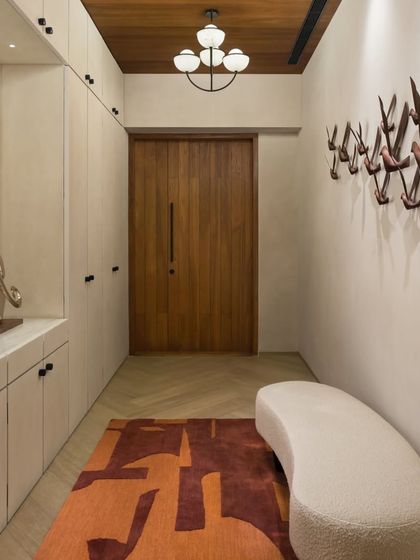 The private entrance lobby of the East Coast Residence is a long, gallery-like space. It features ample built-in storage and a sculptural coat rack, combining functionality with a strong design statement.