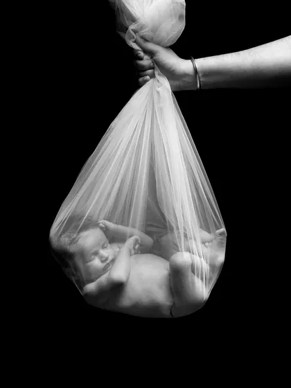 A creative and symbolic newborn shot. This image, showing the baby safely cradled as if being delivered by a stork, is an artistic take on the miracle of new life.