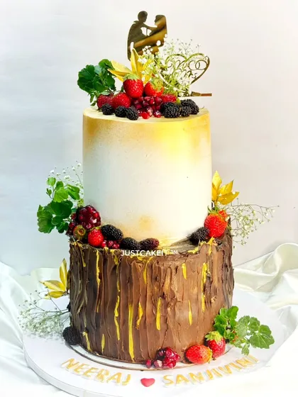 A huge wedding cake with a rustic-chic design. The bottom tier has a realistic chocolate bark texture, topped with a smooth tier and loaded with fresh berries.