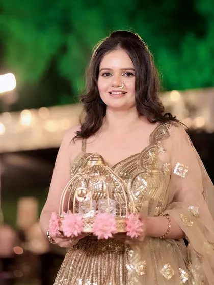 Golden glam for a party. This client is holding a decorative birdcage, looking absolutely charming in her sequined lehenga.