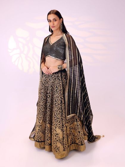 The full look of the black and gold lehenga, showing how the striped dupatta can be draped over the shoulders for a classic, elegant style.