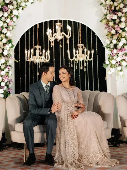 A beautiful portrait of the couple on their reception sofa, framed by a floral arch and hanging crystals. Every detail was curated for elegance.
