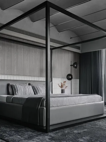In this master bedroom from the Vaulted Haus, we used a four-poster bed to define the volume within the larger space. The headboard wall is a study in texture, combining frosted glass bricks with custom grey veneer strips. This layering of materials, along with the vaulted ceiling and tensioned rope lighting, creates a serene and sophisticated sanctuary.