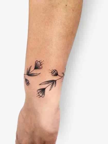 A close-up of the floral wristband, showing the delicate shading on the leaves and the fine details of the flower buds.