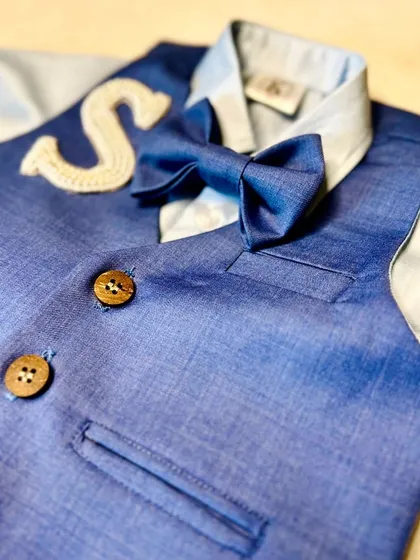 A close-up on the details of our boys' navy suit, showing the texture of the fabric and the beautifully crafted embroidered initial.