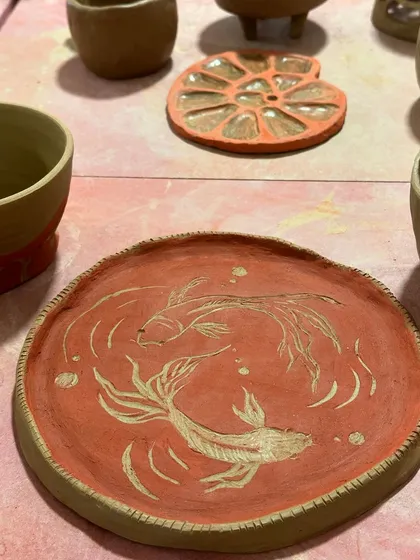 A plate with two koi fish gracefully carved into the surface. An example of sgraffito technique from one of our workshops.