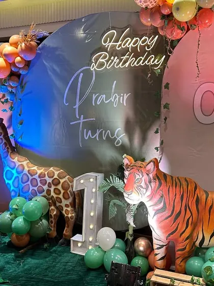 Another take on the popular jungle theme, this setup for Prabir's first birthday includes a tiger, giraffe, and zebra, all set against a backdrop with a custom neon birthday wish.