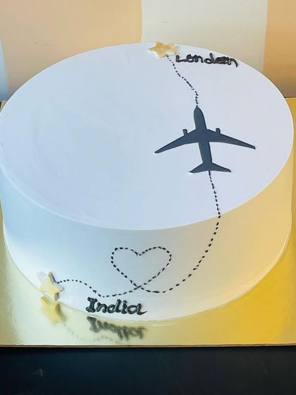 A sweet send-off. This minimalist farewell cake features a plane flying from India to London, making it a thoughtful gift for someone moving abroad.