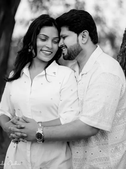 A joyful and intimate black and white portrait. The couple's bright smiles and close embrace create a feeling of warmth and happiness.