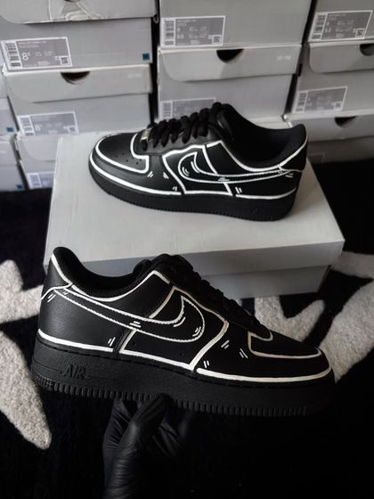 The black cartoon custom sneakers displayed on their box.