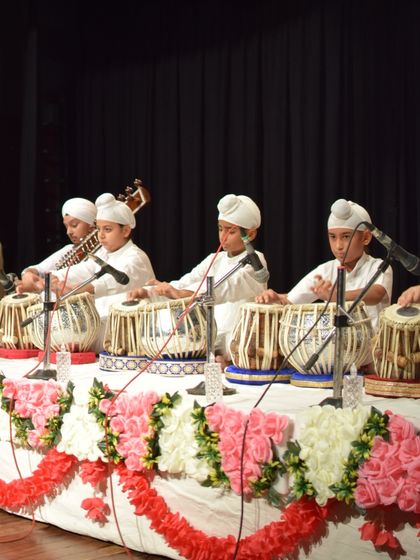 A full ensemble of our students on stage, featuring multiple tabla players and a sitar player. This showcases the blend of rhythm and melody we cultivate.