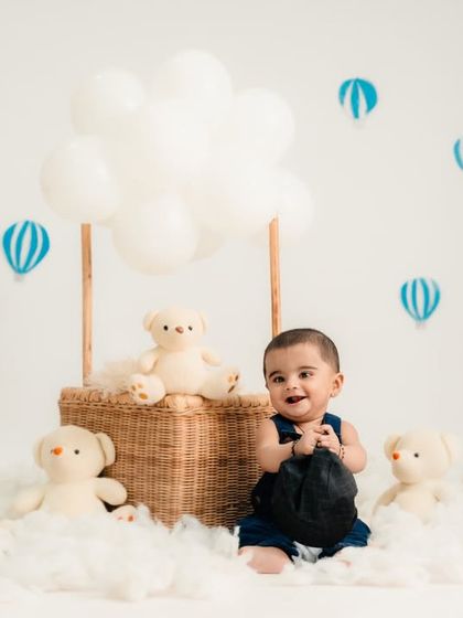 This little adventurer is sitting in a wicker basket "balloon," surrounded by clouds and teddy bear friends.